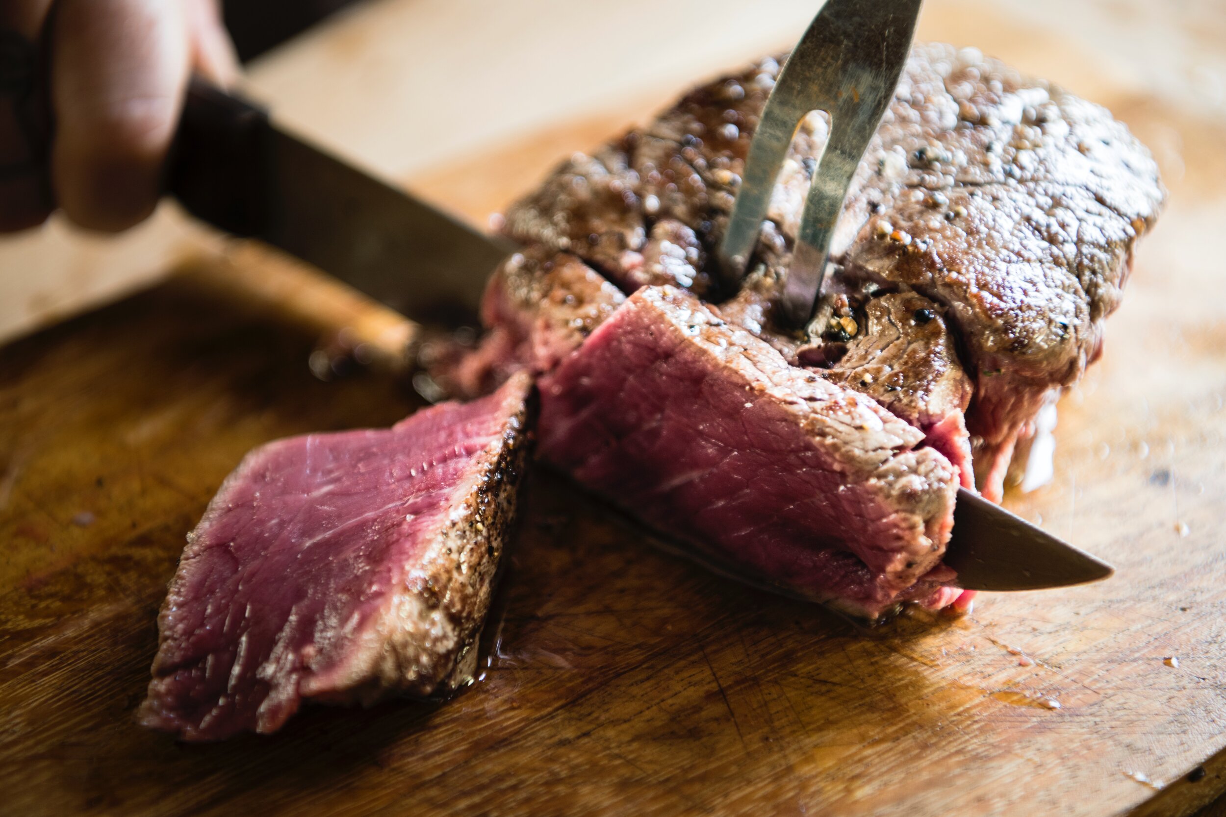 beef-cuisine-cut-1881336 Close-up of a perfectly cooked steak being sliced on a wooden cutting board, showcasing its juicy pink interior and seared exterior, with a knife and fork in action. Ideal for meat lovers and culinary enthusiasts.