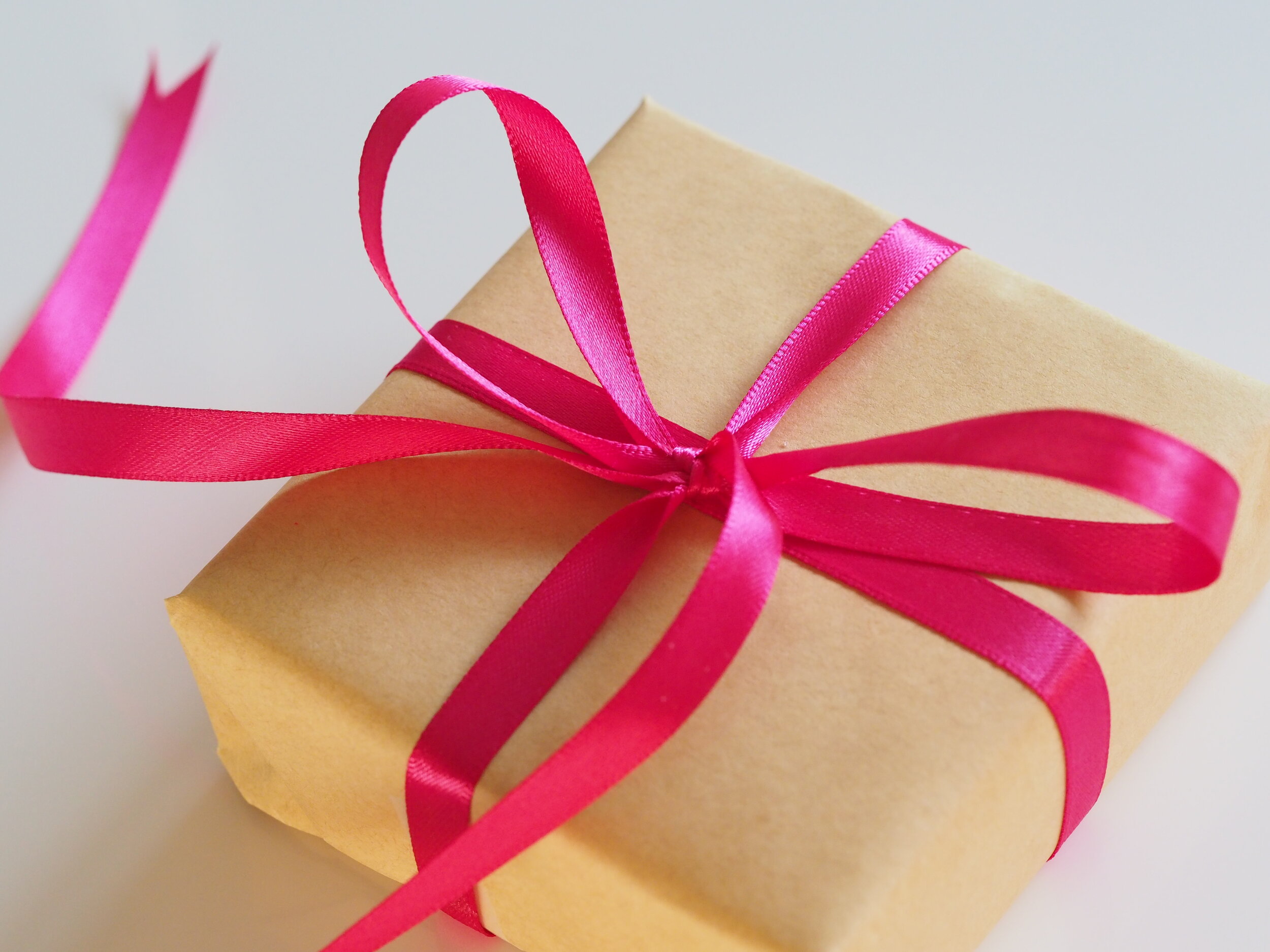 image-asset (2) Brown gift box wrapped in kraft paper and tied with a vibrant pink satin ribbon, perfect for special occasions and celebrations.